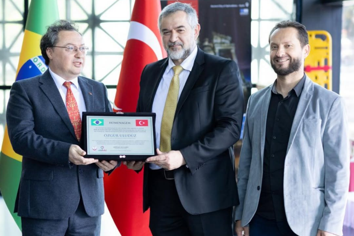 Atividades do MARKAZ - 2026 74 Representantes reunidos em entrega de homenagem com bandeiras do Brasil e da Turquia