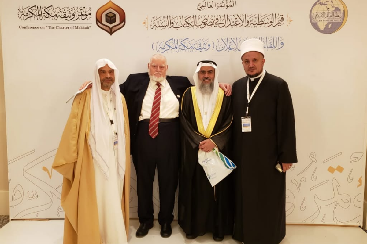 Atividades do MARKAZ - 2026 99 Representantes reunidos diante do painel de conferência sobre a Carta de Meca